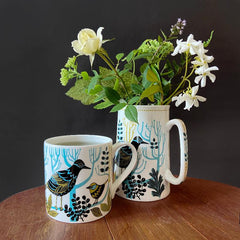 Bird printed matching mug and jug containing garden flowers