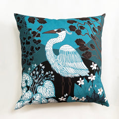 bright blue cushion with white heron print and flowers in black and brown