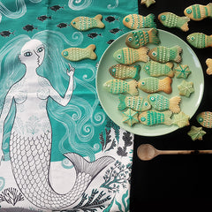 Mermaid print tea towel with a plate of fish-shaped biscuits