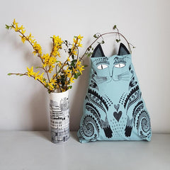 Lush Designs blue cat-shaped kitty cushion with vase of yellow flowers
