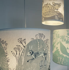 Lush Designs rabbit print shade lit up and hanging with fox and bird lampshades in a group