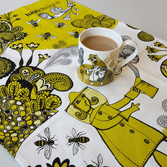 Lush designs Beekeeper and bee print flowery tea towel in yellow-green pictured with beekeeper print mug of tea