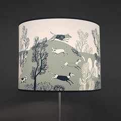 large lampshade on a standard lamp printed with comical dogs running in the countryside