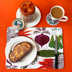 Vegertable print mat with a taosetd cheese sandwich a jar of kimchi and a cup of tea