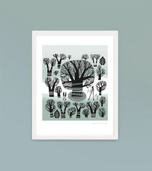 framed print of winter trees in a greyish green landscape against a soft teal wall