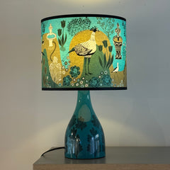 Decorative lamp with a colorful lampshade featuring birds and plants on a neutral background.