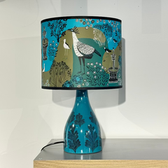 Turquoise patterned lamp base with shade printed with birds and flowers in greens and blues