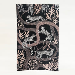 tea towel with design of ocelots in black and white with pale pink trees on a black background