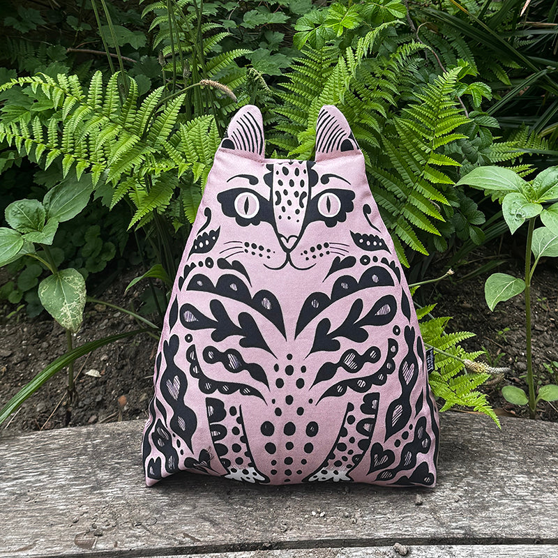 Decorative pillow with animal pattern on a wooden surface with green plants in the background