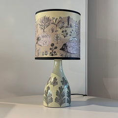 Decorative lamp with a black and white patterned shade on a plain background