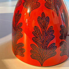 Orange lamp base with black leaf-like patterns on a white background