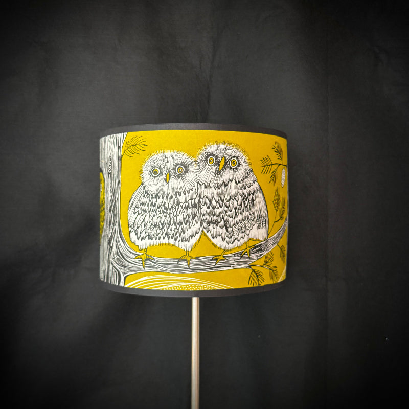 Lampshade with owl design on a yellow background against a dark gray background