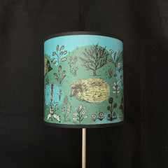 Lampshade with nature-themed design featuring plants and a hedgehog on a dark background