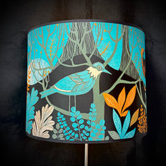 Decorative lampshade with bird and floral design on a black background