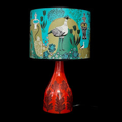 Lamp with a colorful lampshade featuring a bird design on a black background