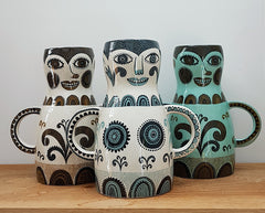 three printed vases, brown, blue and green, shaped like women with hands on hips