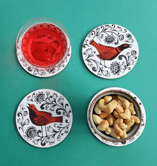 Coasters on a table with a glass of punch and some cashew nuts