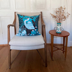 wooden chair with linen seat bearing a bright blu and black cushion printed with a heron