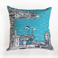 Cushion printed with seaside cove, a village and dolphins in a bright blue sea