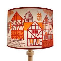 Lush Designs lampshade on a wooden lamp base, printed with half-timbered houses in orange and red