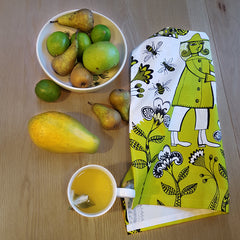 Lush Designs Beekeeper print tea towel next to green and yellow fruit