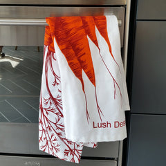 Carrot print tea towel pictured in the kitchen hanging on cooker