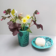 Lush Designs turquoise ceramic beaker with spring flowers in it, and soap dish with frothing soap
