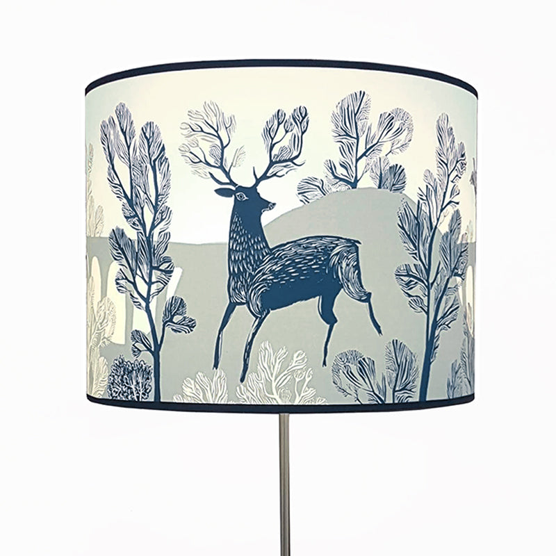 Large lampshade on a lamp printed with a blue stag in the countryside