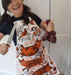woman wearing cat print apron with big kitchen knife and beetroot