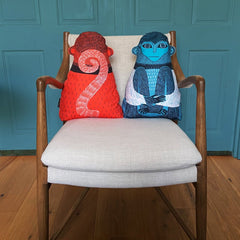 Orange and blue monkey-shaped ushions on a wood framed upholstered chair